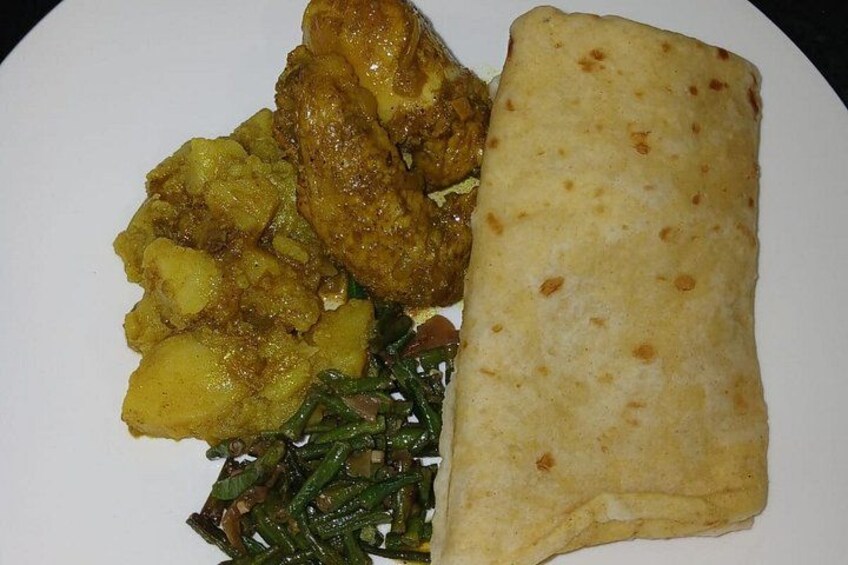 A plate with a piece of flatbread, a curry with potatoes, and a side of green vegetables. 3