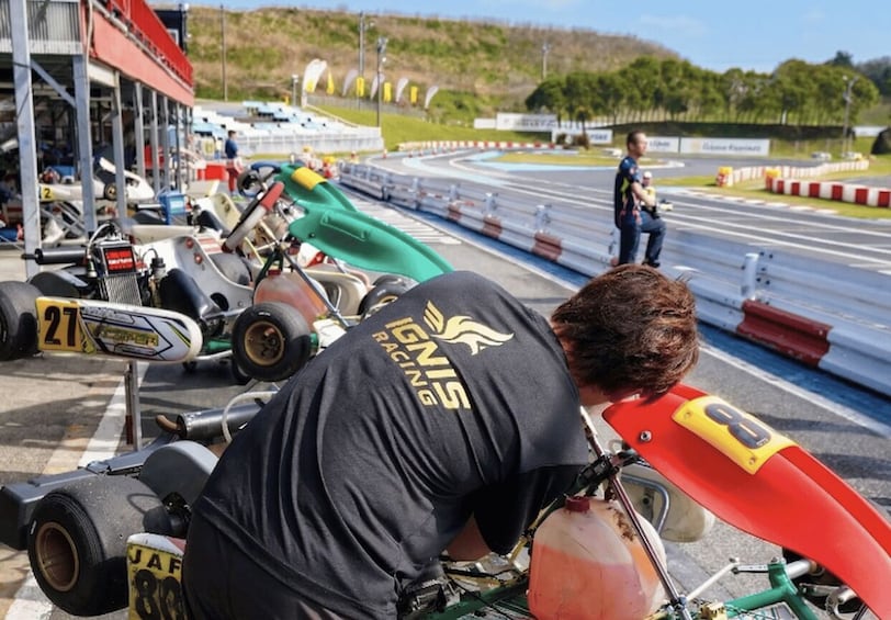 A go-kart racing track with multiple go-karts and a person in a black shirt with 'IGNIS RACING' on the back. 2