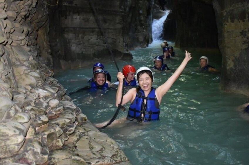 Menschen in einer Höhle bei Wasser, mit Helmen und Schwimmwesten. 1