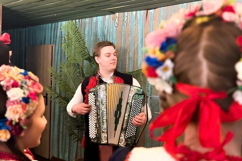 A person playing accordion in front of a group of people. 5