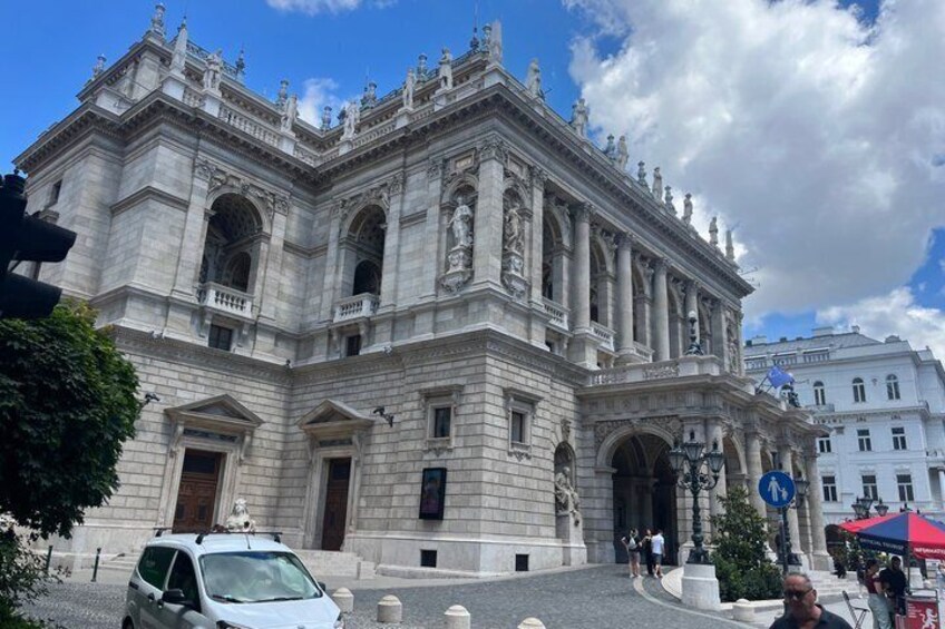 A historic building with ornate architecture, a large arched entrance, and a statue on the roof. 2