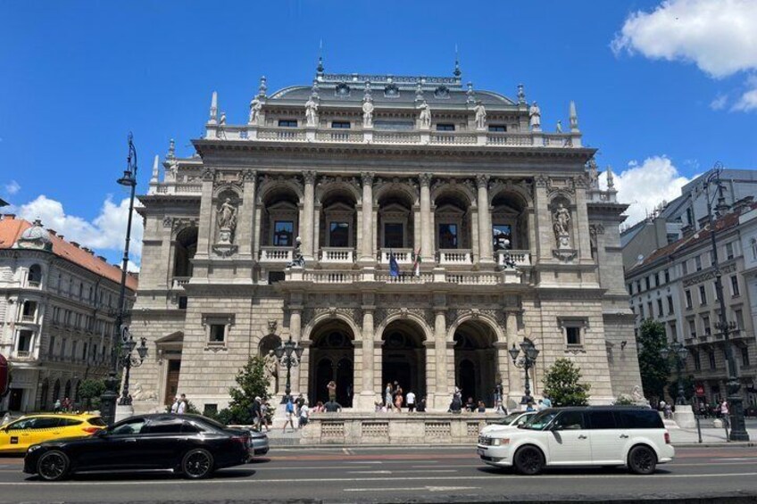 A historic building with classical architecture, a street with cars, and a clear blue sky. 4