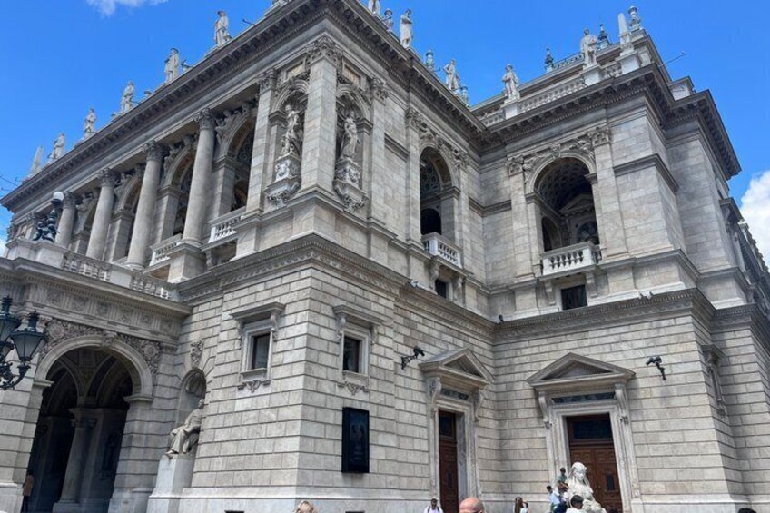 A large, ornate building with classical architecture, featuring columns, statues, and detailed carvings. 5