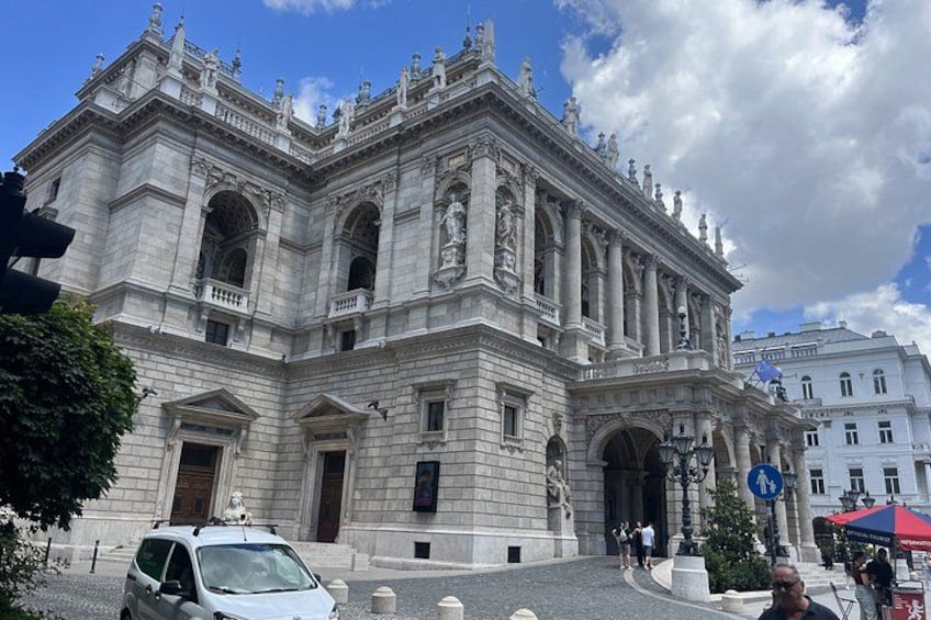 A historic building with ornate architecture, a large arched entrance, and a statue on the roof. 3