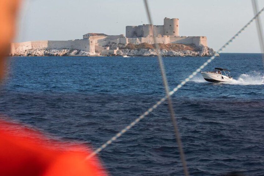 A boat speeding past a historic castle on a calm sea. 4
