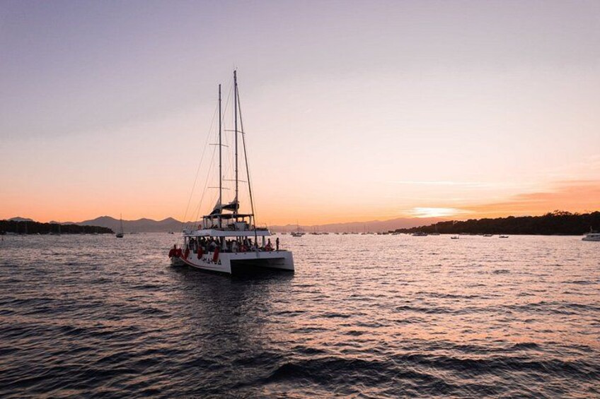 Un voilier transportant des passagers sur une étendue d’eau calme, au coucher du soleil. 4