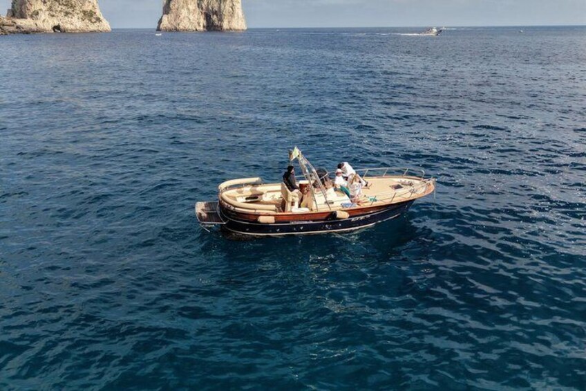 Un petit bateau sur une eau bleue et calme, avec des affleurements rocheux en arrière-plan. 1