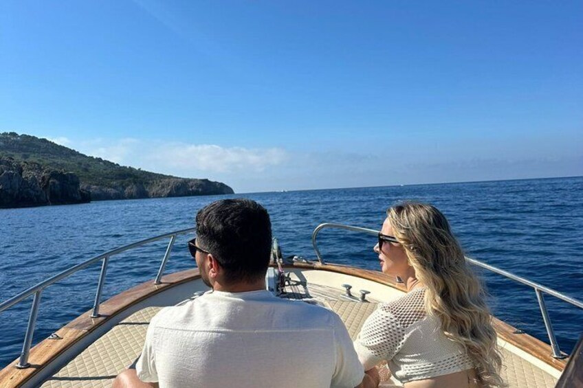 Un couple est à bord d’un bateau, avec une vue sur la mer et une côte lointaine. 2