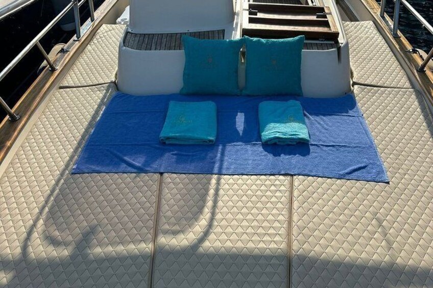 Une terrasse ensoleillée avec une serviette bleue et des coussins. 4