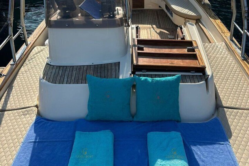 Un pont de bateau avec une serviette bleue, deux coussins turquoise et un banc en bois. 3