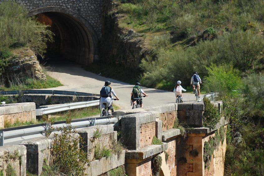 Des cyclistes sur un pont, avec un pont en arc de pierre en arrière-plan. 3