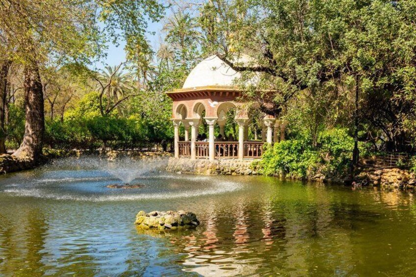 Un belvédère au bord d’un étang orné d’une fontaine, entouré d’arbres et de verdure. 4
