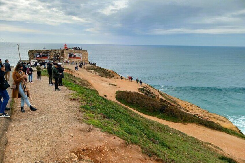 Une promenade en bord de mer, avec des passants, un phare et la mer. 1
