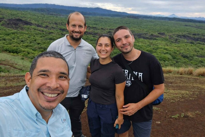A group of people standing on a hill with a view of a green landscape and distant mountains. 3