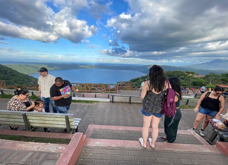A group of people at a scenic overlook with a view of a lake and mountains. 2