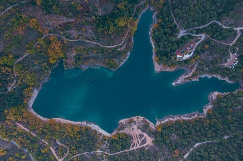 A large body of water surrounded by forested areas with visible roads and a small building. 3