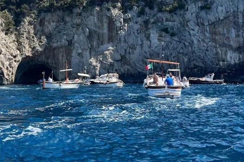 Imbarcazioni ancorate vicino a una costa rocciosa con l'ingresso di una grotta. 2