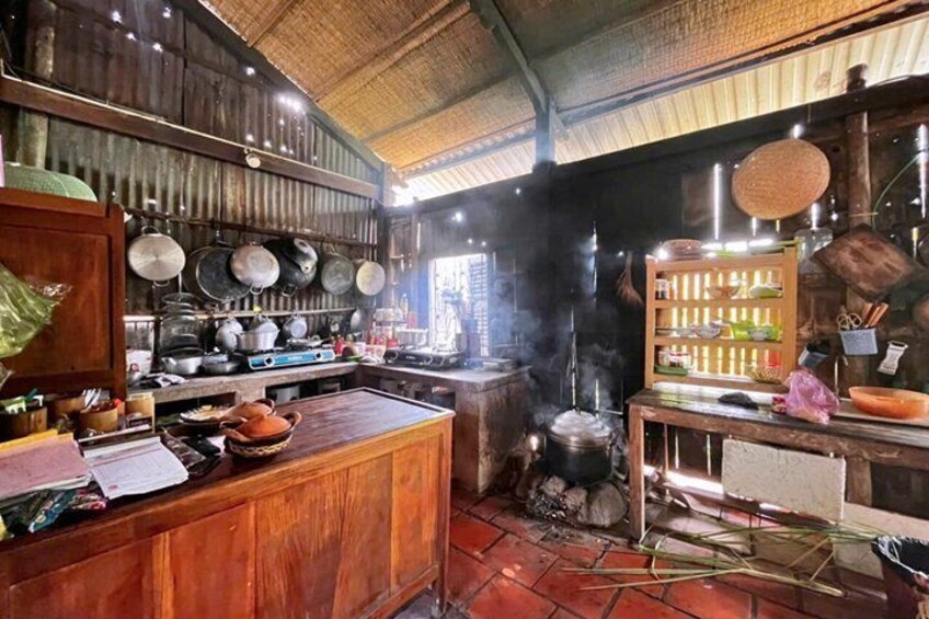 Une cuisine rustique avec des plans de travail en bois, des casseroles suspendues et un poêle traditionnel. 1