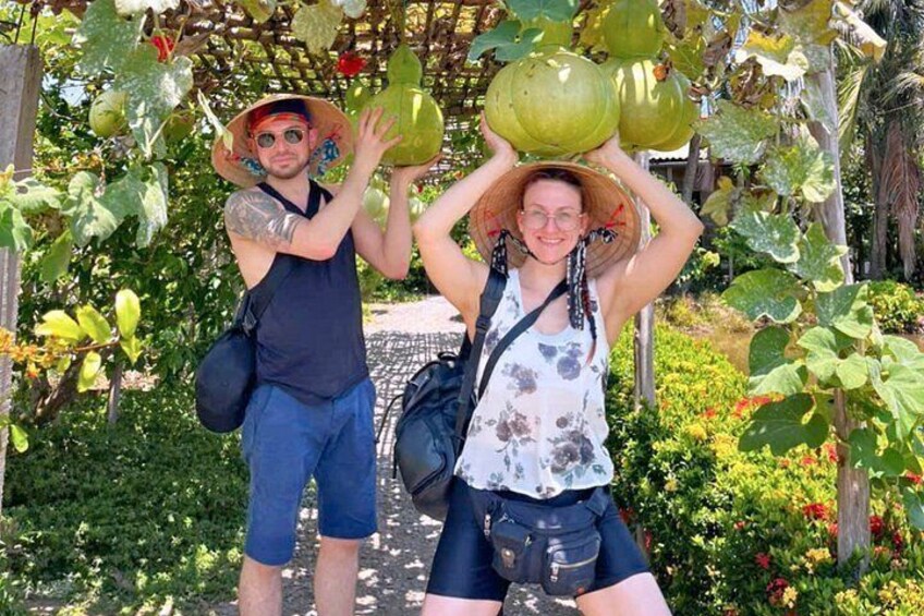 Deux personnes tenant des pastèques dans un jardin agrémenté d’une pergola en bois et d’une végétation luxuriante. 5