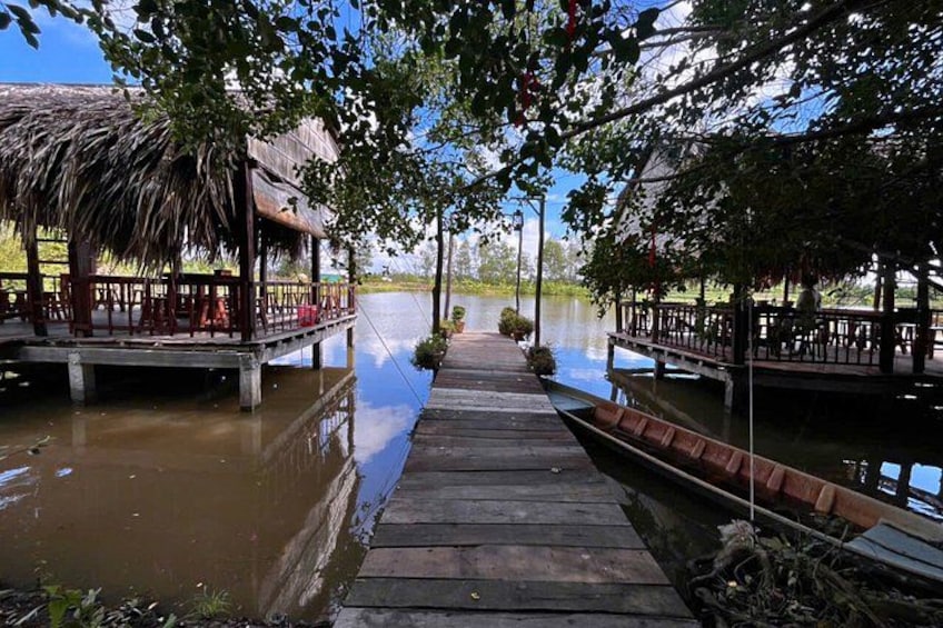 A wooden dock leading to a thatched-roof structure by a calm body of water. 5