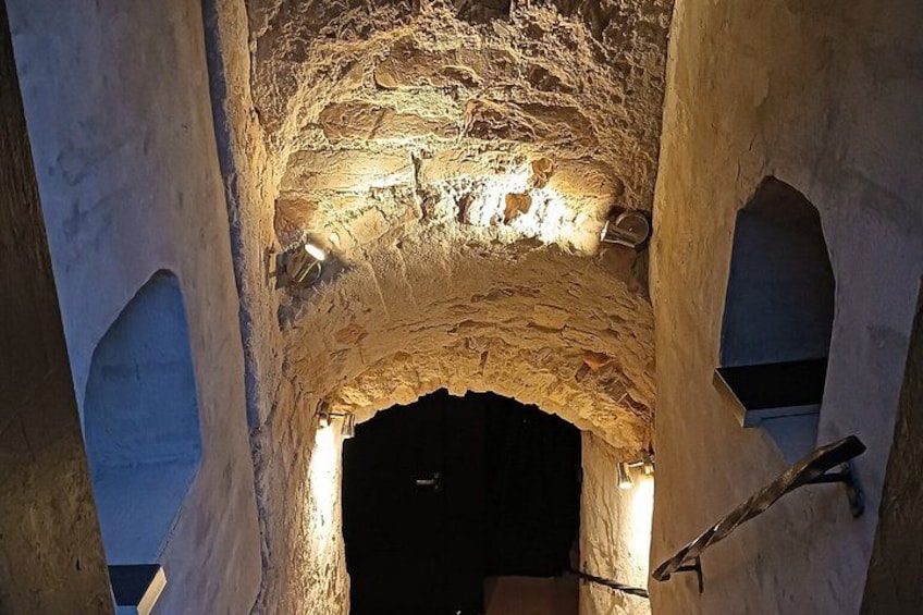 Une structure ancienne en pierre, dotée d’une entrée en arc de cercle et éclairée par une lumière artificielle. 4