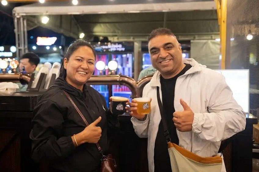 Two people at a food stall, one holding a coffee cup. 1