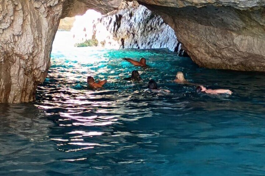 A group of people swimming in a natural pool under a rocky cave. 4