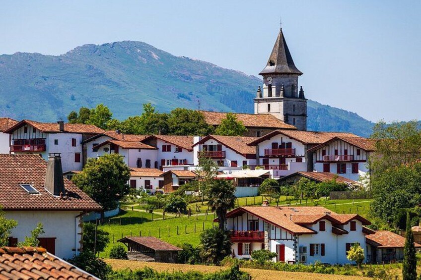 A village with traditional buildings, a church with a bell tower, and a mountain in the background. 1