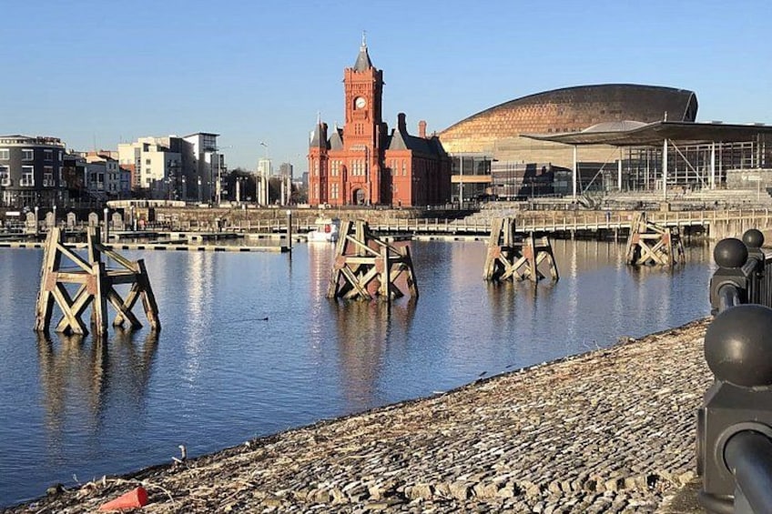 Un río con estructuras de madera, una torre del reloj roja y un edificio moderno. 5