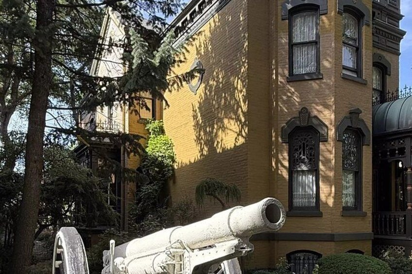 A cannon in front of a yellow building with ornate windows and a balcony. 3