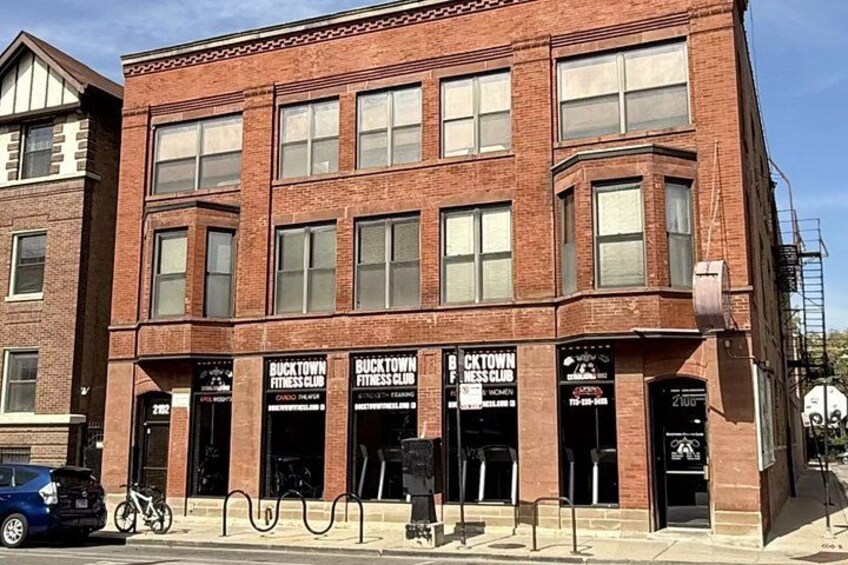 A brick building with multiple storefronts, including a fitness club. 4