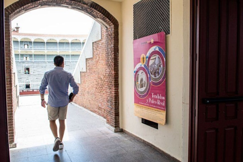A man walking through a corridor with a poster on the wall. 5