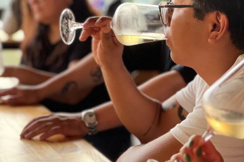 Una persona sosteniendo una copa de vino, sentada a una mesa. 5
