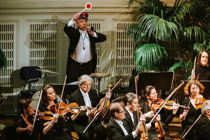 Un director de orquesta liderando a músicos tocando instrumentos de cuerda. 2