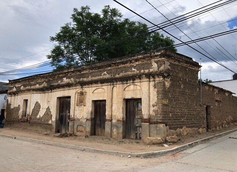 An old, weathered building with arched windows and doors, surrounded by trees and power lines. 5