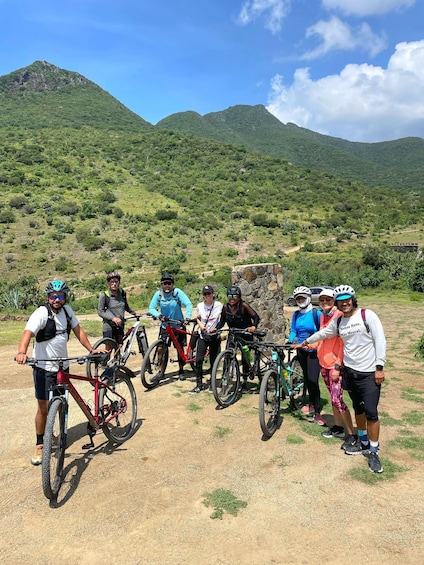 A group of cyclists on a dirt path with mountains in the background. 2