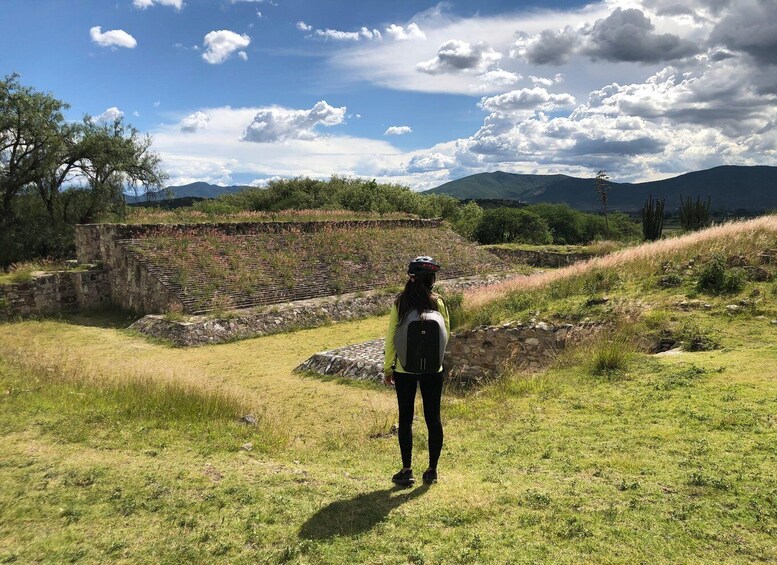 A person standing on a grassy field with a stone structure in the background. 5