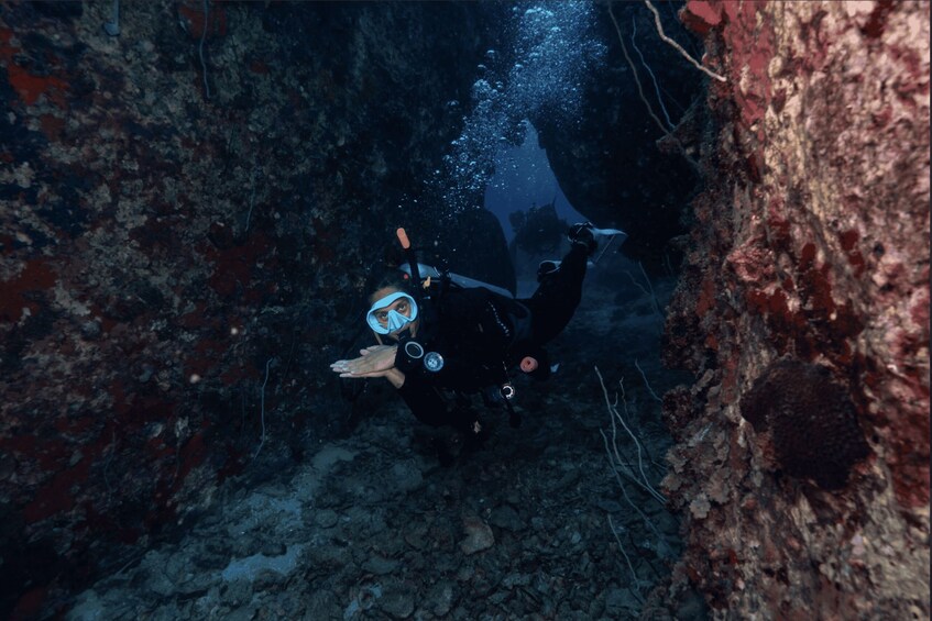 A diver in a cave with visible rock formations and water bubbles. 3
