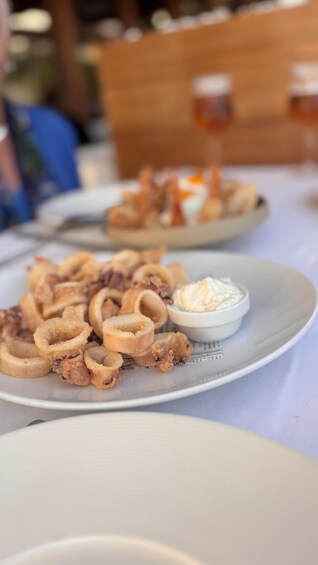 A plate of fried calamari and a small bowl of dipping sauce. 5