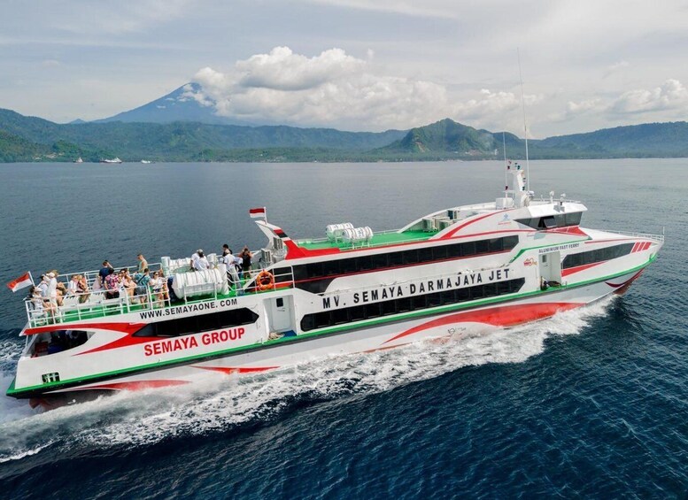 A ferry with passengers, branded 'SEMAYA GROUP,' traveling on a body of water with mountains in the background. 1