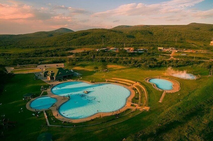 Un resort con varias piscinas rodeado de verdes colinas. 2