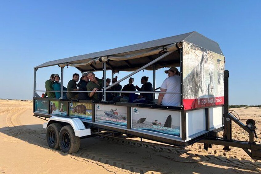 Ein Safarifahrzeug mit Passagieren am sandigen Strand. 3