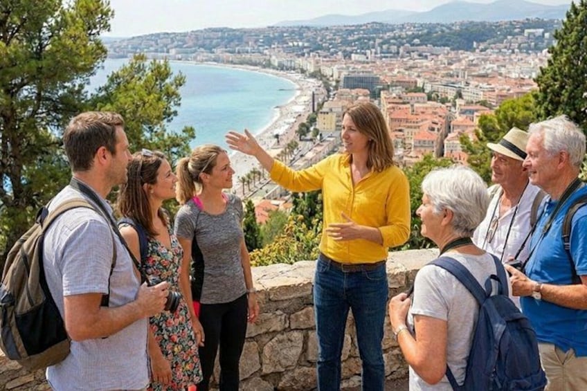 Un groupe de personnes se tient sur une corniche rocheuse, d’où elles dominent un paysage urbain situé sur la côte. 2