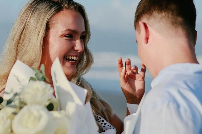 A person holding a bouquet of flowers, another person with an open hand, and a clear sky in the background. 3