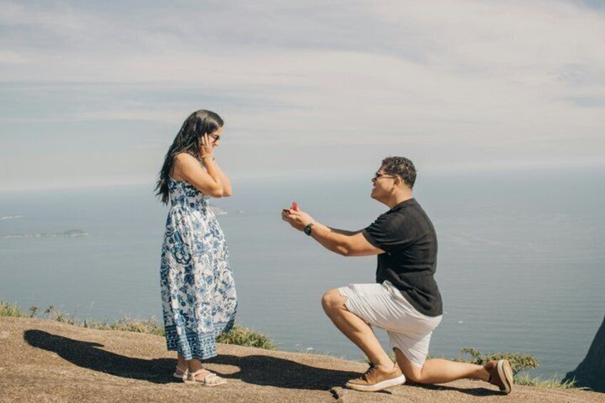 A man proposing to a woman on a cliff overlooking the ocean. 4
