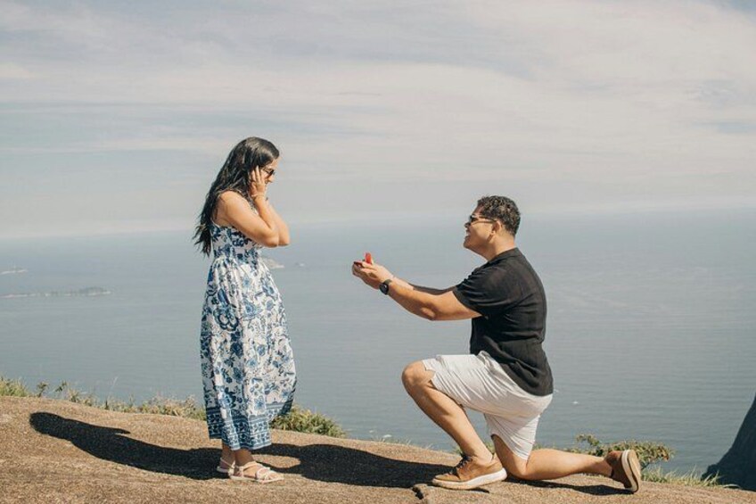 A man proposing to a woman on a cliff overlooking the ocean. 4