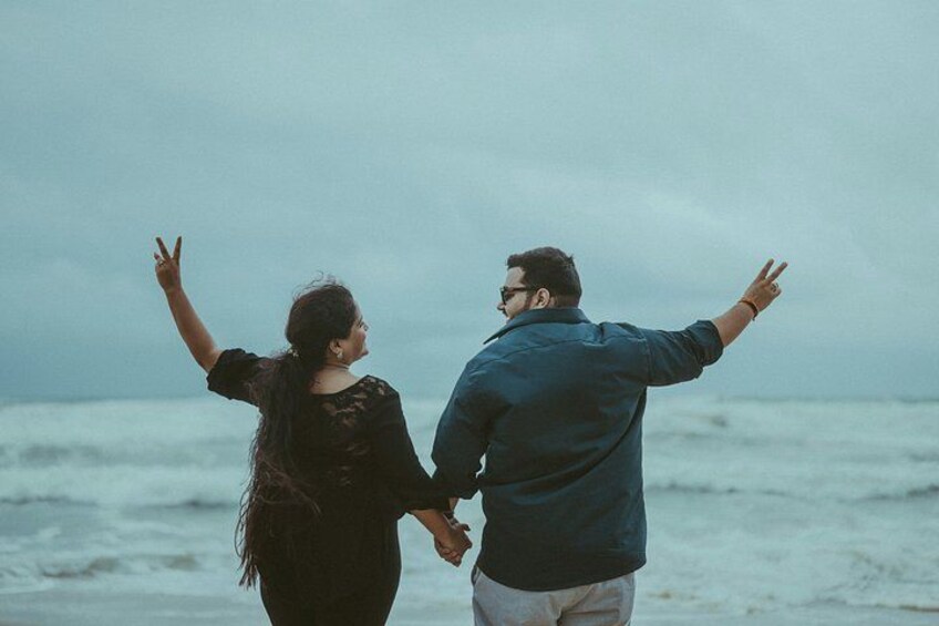 A couple holding hands and facing the ocean. 5