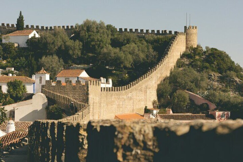 A stone wall with a tower, surrounded by buildings and trees. 3