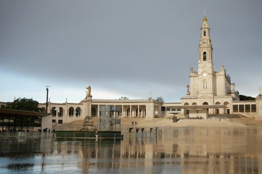 A large church with a tall bell tower, a fountain, and a statue in front. 5