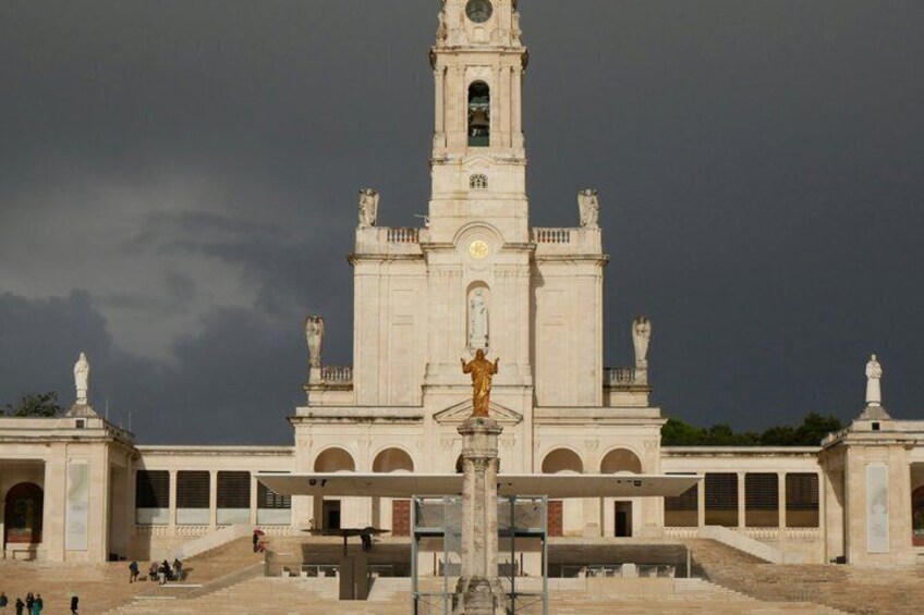 A large white church with a bell tower and a statue in front. 4